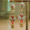 Ornate earrings with gold, red, and pearl details on a reflective surface.