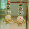 Ornate gold earrings with red and green gemstones on a stand.