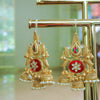 Ornate gold earrings with red centers on a gold stand.