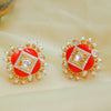 Pair of red earrings with gold and pearl accents on a beige background