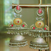 Ornate gold and silver earrings with red stones on a stand.