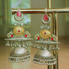Ornate silver and gold earrings with red stones on a stand.