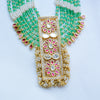 Ornate gold necklace with green beads and pink stones on a white background