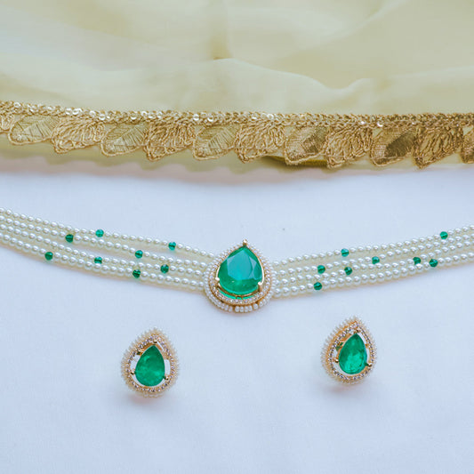 Jewelry set with green gemstones and pearl necklace on a white background