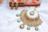 Ornate gold and green jewelry set with earrings on a white background