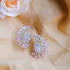 Pair of pink and silver earrings on a beige fabric background with a white rose.