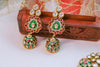 Ornate earrings with green, red, and gold colors on a white surface.