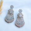 Pair of ornate earrings with clear gemstones on a light background