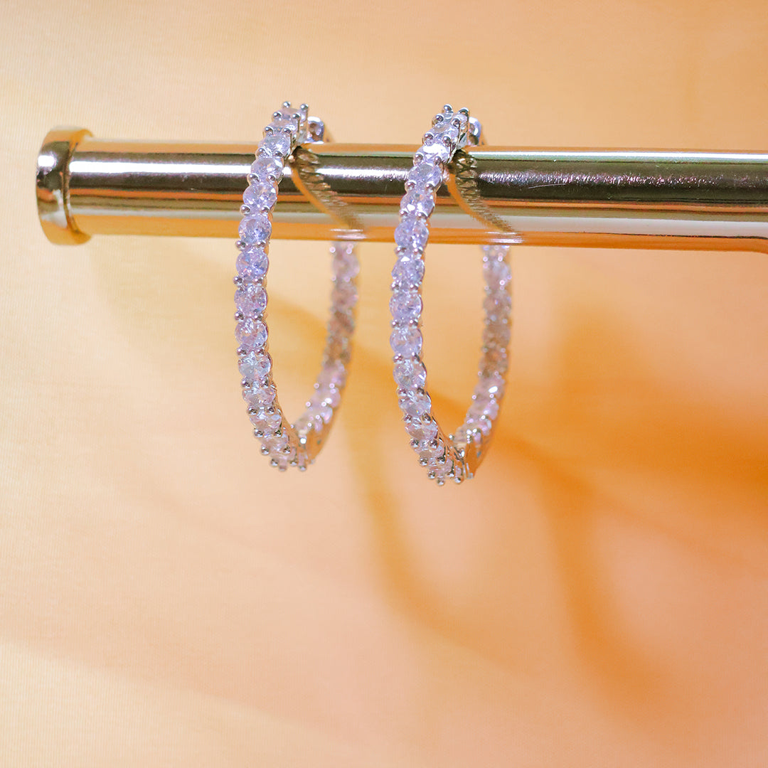 Pair of diamond hoop earrings on a gold rod with a blurred orange background